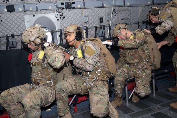 Military free fall instructors from the U.S. Army John F. Kennedy Special Warfare Center and School check each other's parachutes before jumping onto Phillips Drop Zone at Yuma Proving Ground, Arizona.
