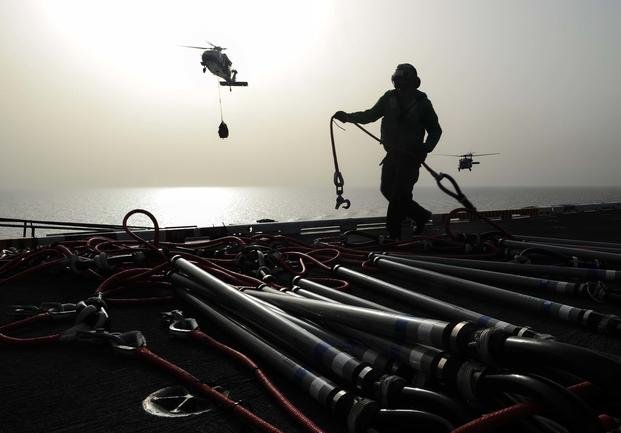A sailor organizes cargo retrieval cables on the flight deck after MH-60S Sea Hawk helicopters assigned to the Sea Knights of Helicopter Sea Combat Squadron (HSC) 22 transfers cargo to the aircraft carrier USS Theodore Roosevelt