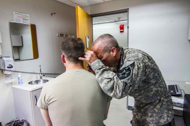 Maj. Roger Williams looks inside the ear of a patient to check the patient's condition at the TMC in Camp Humphreys.