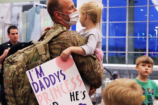 soldier holding child with homecoming sign