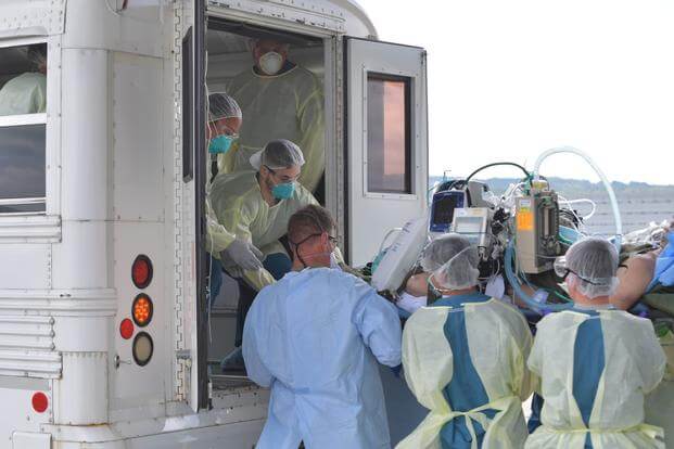 Airmen transfer a COVID-19 patient following the first-ever operational use of the negatively pressurized conex aboard a C-17 Globemaster III aircraft.