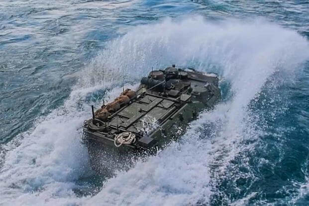 An amphibious assault vehicle splashes into the water.