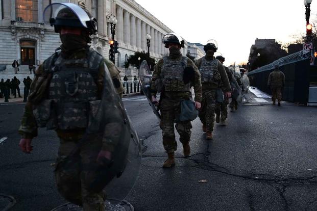 National Guard soldiers walk down the street near the U.S. Capitol Building.