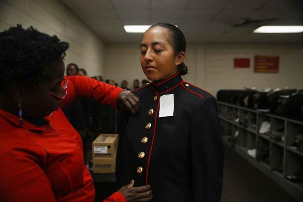 A tailor examines the uniform of a recruit.