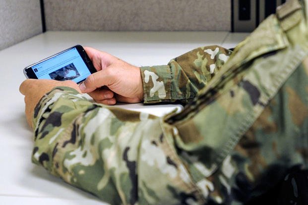 A soldier looks at social media on a cellphone