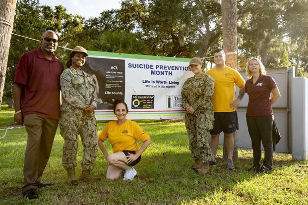 Sailors and civilians pose for a photo in recognition of Suicide Awareness Month.