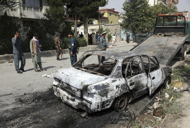 Security personnel inspect a damaged vehicle where rockets were fired from in Kabul, Afghanistan