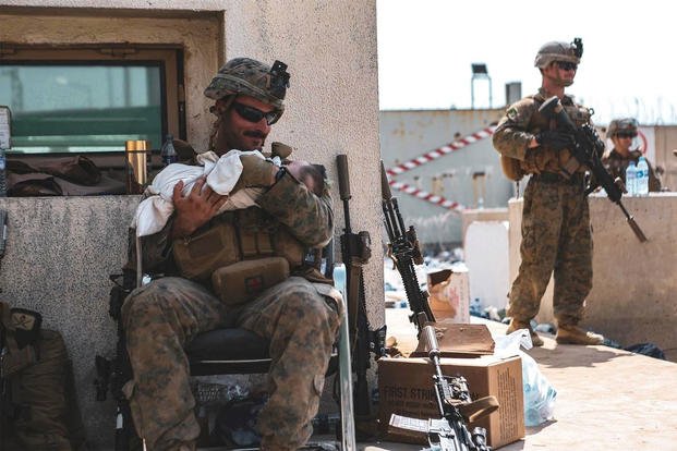 U.S. military service members comfort infants at Hamid Karzai International Airport in Kabul, Afghanistan.