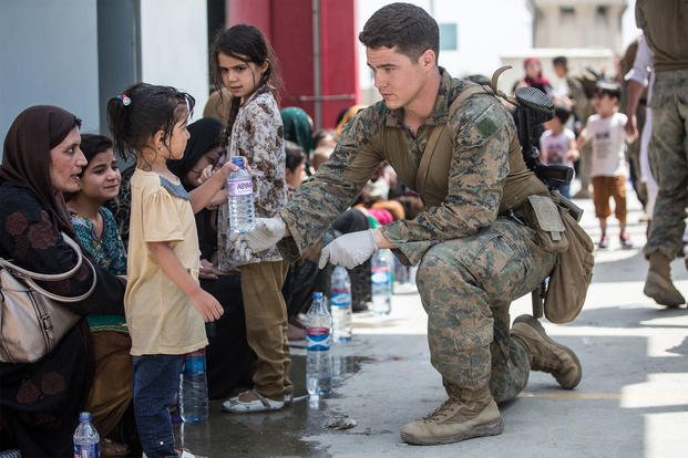 U.S. Marine Corps Marines from the 24th Marine Expeditionary Unit and U.S. Navy Corpsmen with Special Purpose MAGTF - Crisis Response - Central Command provide fresh water to children at Hamid Karzai International Airport in Kabul, Afghanistan.