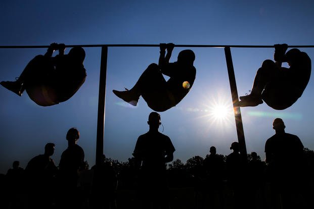 Cadets perform leg tucks at sunrise.