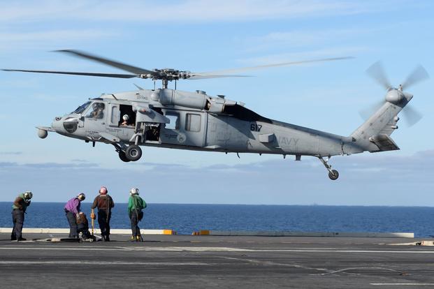 An MH-60S Sea Hawk helicopter lands on the flight deck of the aircraft carrier USS Nimitz.