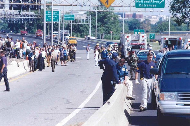 Pentagon employees, law enforcement, and emergency response teams gather on VA-110 near the North Parking Lot, 11 September 2001.
