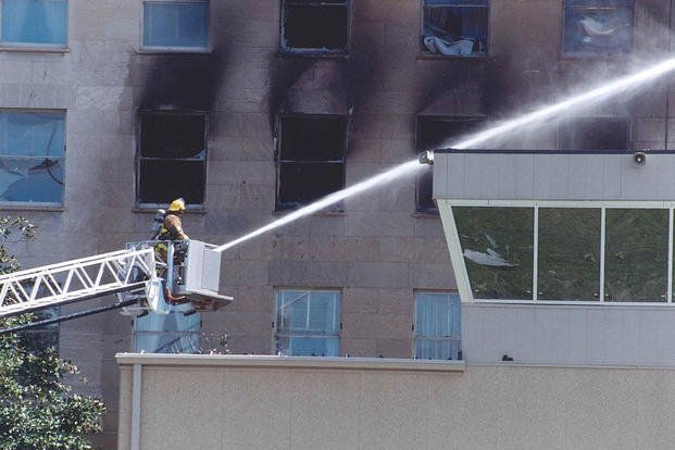 A firefighter works to put out fires burning in the E Ring of the Pentagon near the heliport control tower, 11 September 2001. 