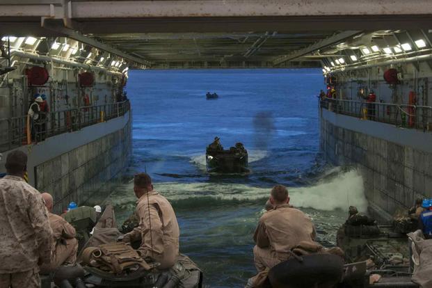 U.S. Marines observe the approach of amphibious assault vehicles
