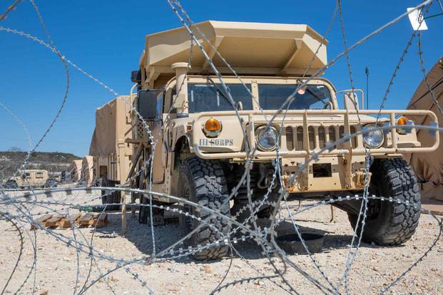 A Humvee sits behind a concertina wire