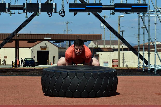Airman flips a tire during physical training.