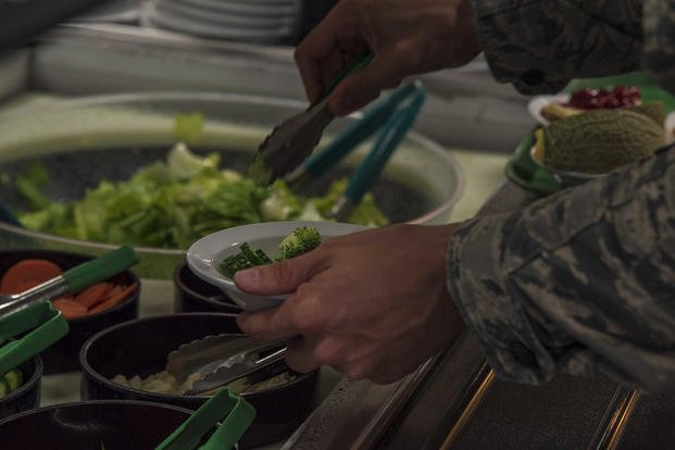 An airman fills his plate from a salad bar.