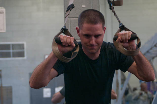 A special ops team member pushes himself during a TRX workout.