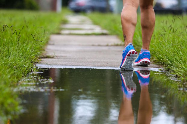 A runner is reflected in a puddle