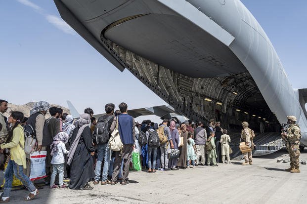 U.S. Airmen and U.S. Marines guide Afghan evacuees aboard a C-17 Globemaster
