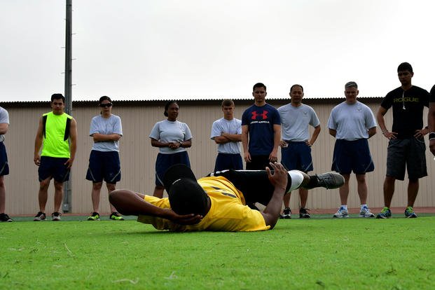 An airman instructs members of Osan Air Base on how to do oblique crunches.