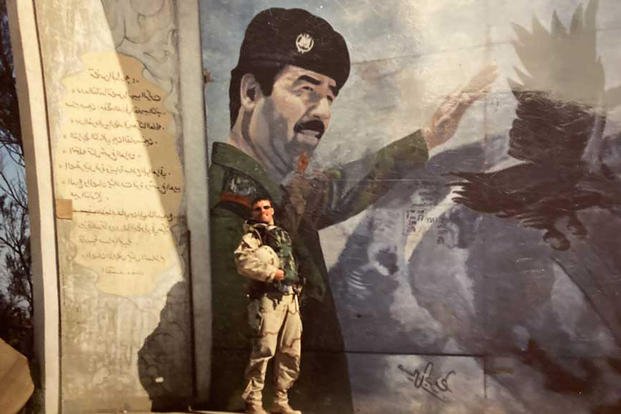Morgan Lerette stands in front of a mural of Saddam Hussein during the ground offensive in 2003