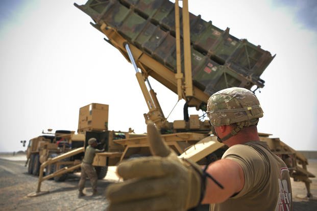 A U.S. Army soldier signals to a colleague while working near a Patriot missile battery at Al-Dhafra Air Base.