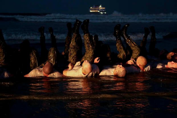 SEAL candidates perform physical training on the beach during BUD/S training.