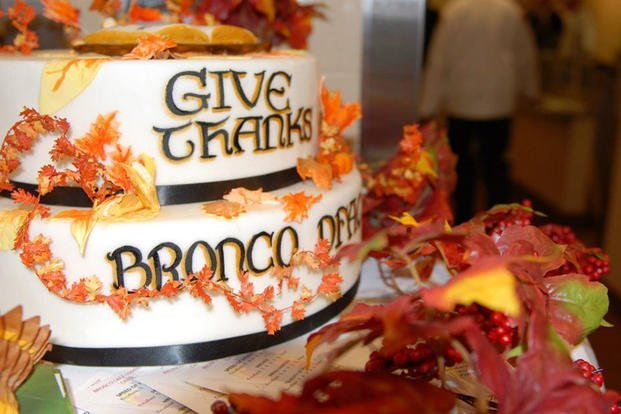 Soldiers showcase a cake as they serve Thanksgiving dinner at Schofield Barracks.