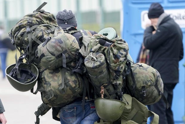 A man carries combat gear as he leaves Poland to fight in Ukraine.