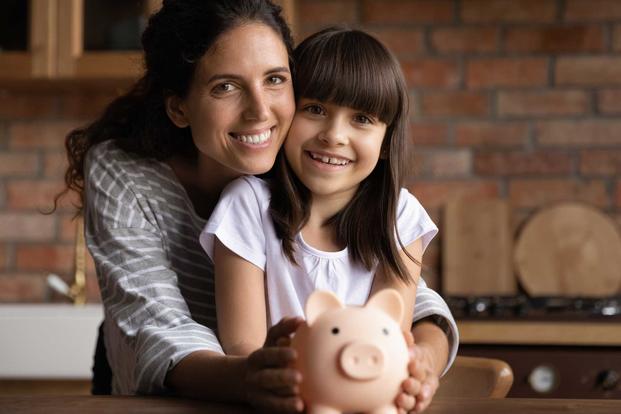 Mother holding daughter who has piggybank