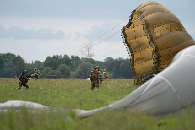 U.S. service members gather their parachutes after a jump during the D-Day 75 commemorative airborne operation in Sainte-Mere-Eglise, France.