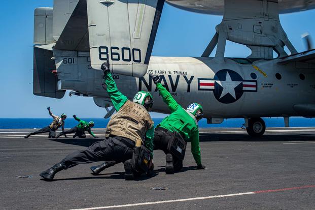 Navy Sailors use hand signals to launch an E-2D Hawkeye on the USS Harry Truman. 