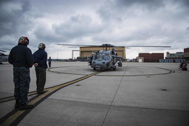 Sailors prepare for an MH-60S Sea Hawk helicopter to take off.
