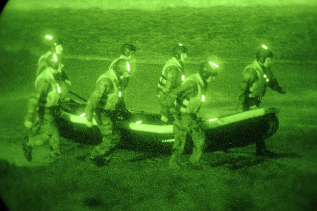 Basic Underwater Demolition/SEAL class students carry an inflatable boat during a first phase navigation training exercise.