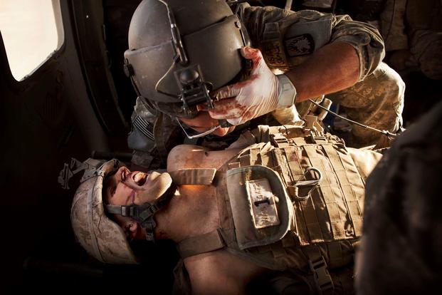 An Army flight media cares for a seriously wounded Marine on board a medevac helicopter.