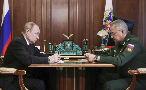 Vladimir Putin listens to Russian Defense Minister Sergei Shoigu.