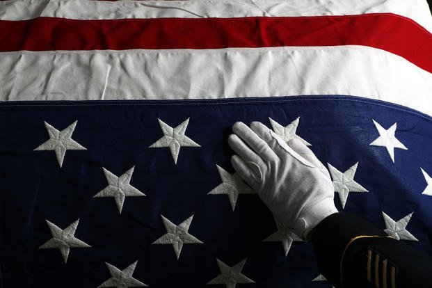 A member of the Honor Guard places his hand on a casket.