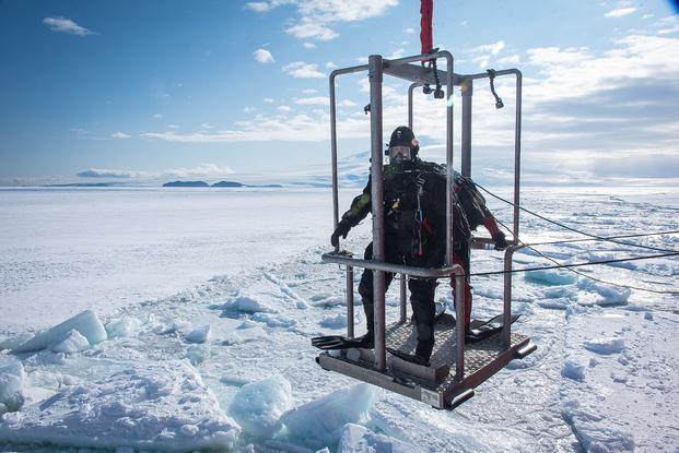 Two scuba divers are lowered to the ice from the U.S. Coast Guard Cutter Polar Star.