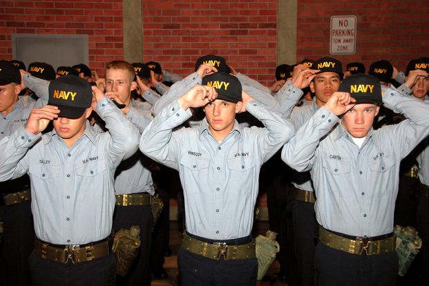 Recruits from Division 253 place Navy ball caps on their heads during a capping ceremony after ending training for Battle Stations 21 on board USS Trayer (BST 21) at Recruit Training Command.