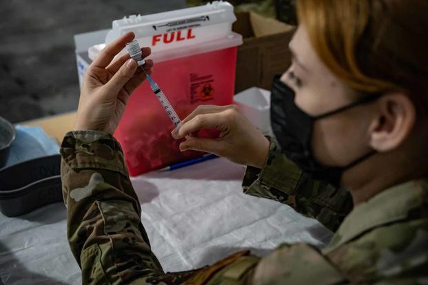 Airman prepares a syringe for a COVID-19 vaccination.