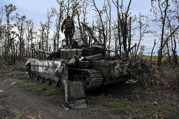 Ukrainian soldier standing atop an abandoned Russian tank.