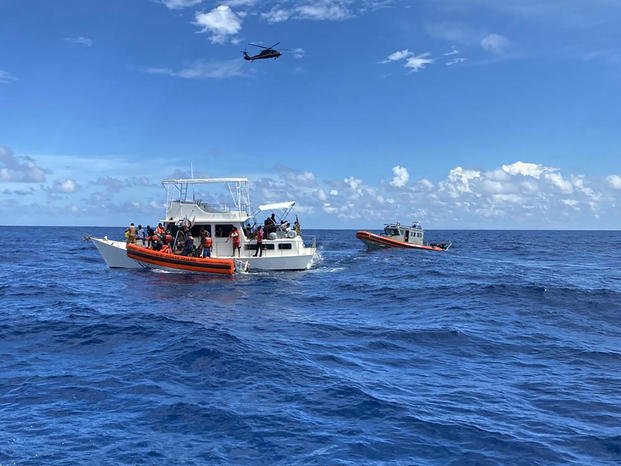 Coast Guard law enforcement crews aiding people from an unsafe and overloaded 40-foot cabin cruiser