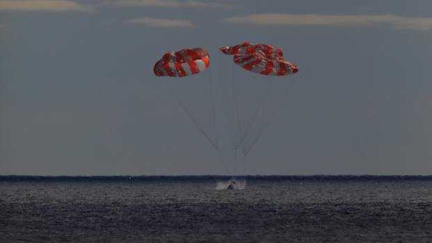 The Orion spacecraft splashes down in the Pacific Ocean.