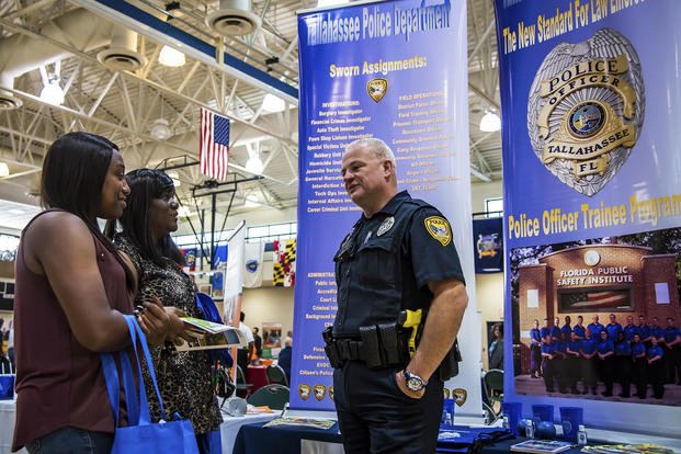 A Tallahassee Police Department policeman speaks to two contract custodians during a veterans career fair at Moody Air Force Base, Ga.