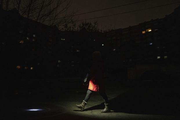A woman lights up the road with a flashlight during blackout in Kyiv, Ukraine.