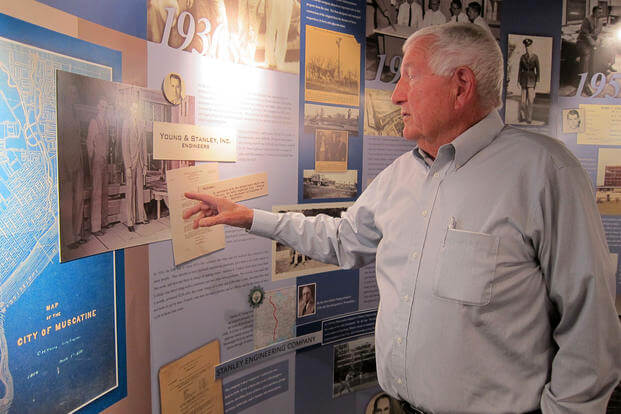 John Sayles, a planner at Stanley Consultants, gestures at a display of the company’s history at its headquarters in Muscatine, Iowa.