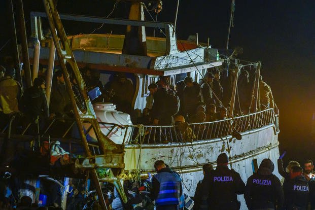 Police check a fishing boat with some 500 migrants in an Italian port.