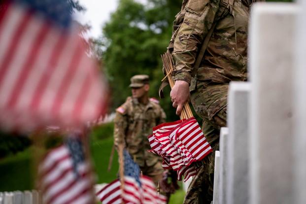 Members of the 3rd U.S. Infantry Regiment place flags in front of each headstone at Arlington National Cemetery.
