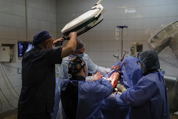 Petro Nikitin, left, takes part in a surgery operation of a Ukrainian serviceman